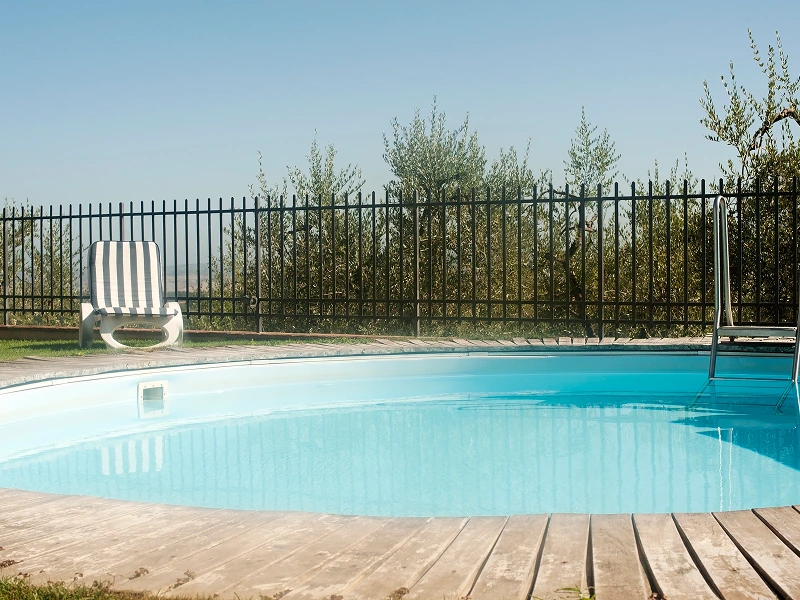 Round pool, striped chair, metal fence.